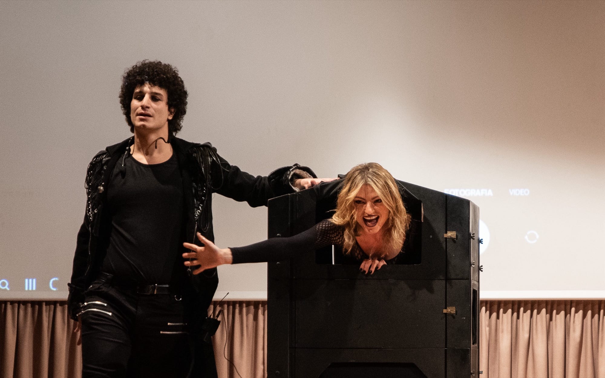Matteo Angrisano sul palco accanto alla sua assistente, che sporge dalla cassa di una grande illusione